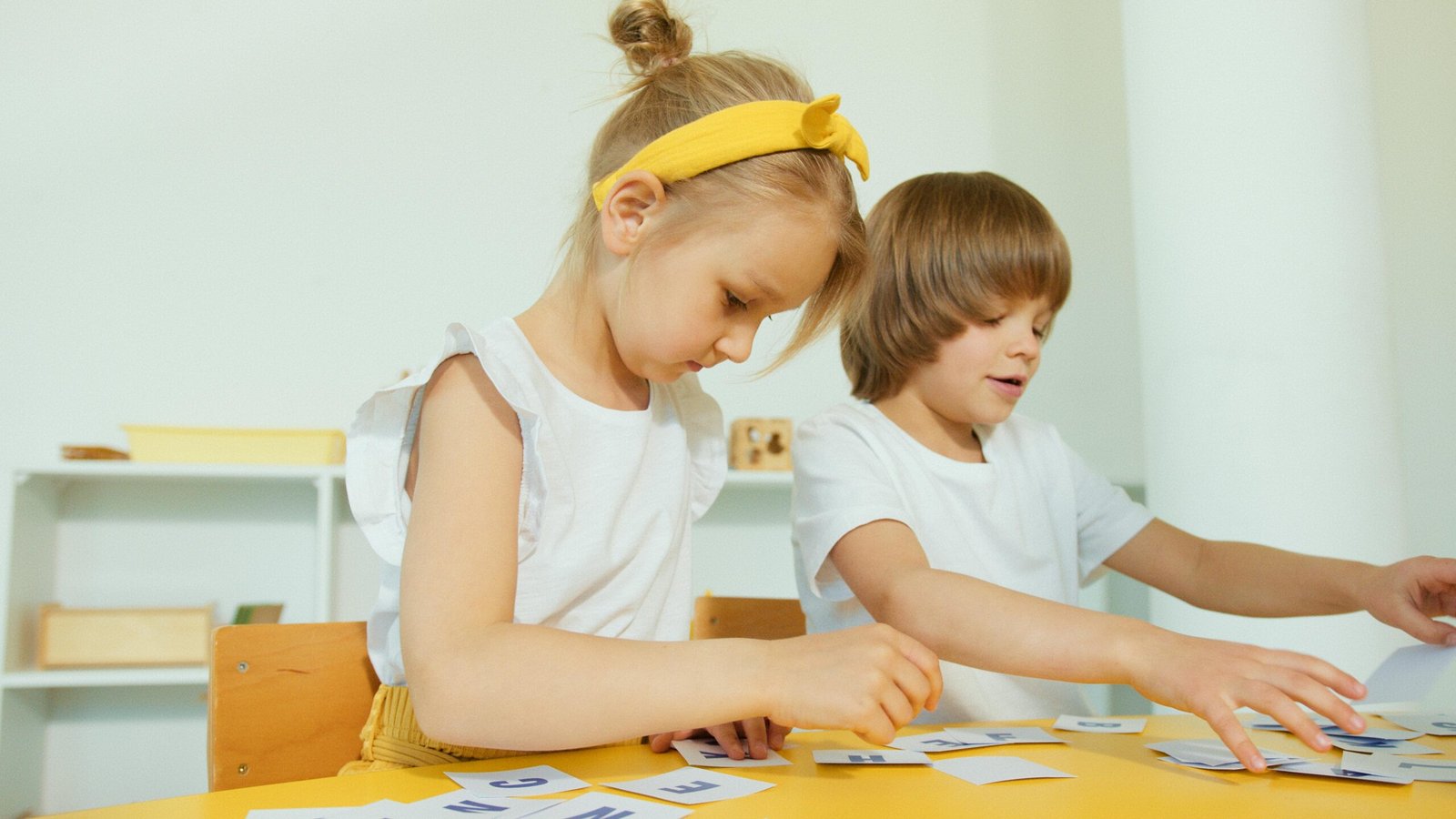 Two young children engaged in a fun learning activity indoors, focusing on letters.